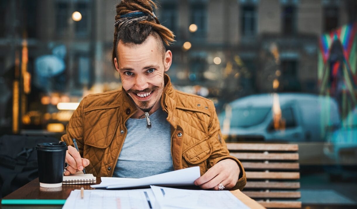 Cheerful Hipster With Sketchbook In Urban Cafe 6YZVMKW 1220x715