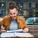 Cheerful Hipster With Sketchbook In Urban Cafe 6YZVMKW 150x150