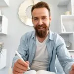 Young Bearded Man Sitting At The Desk And Taking N AP4SLGL 150x150